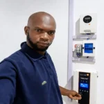 John Tanko, solar inverter builder and installer, next to a real hybrid solar inverter system installation